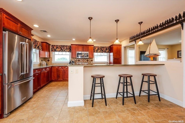 kitchen with kitchen peninsula, tasteful backsplash, stainless steel appliances, hanging light fixtures, and a breakfast bar area