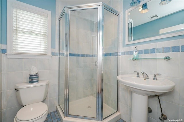 bathroom featuring walk in shower, toilet, and tile walls