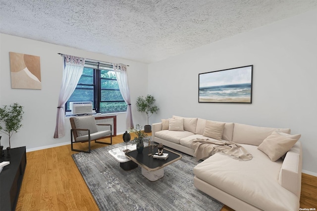 living room with cooling unit, a textured ceiling, and hardwood / wood-style flooring