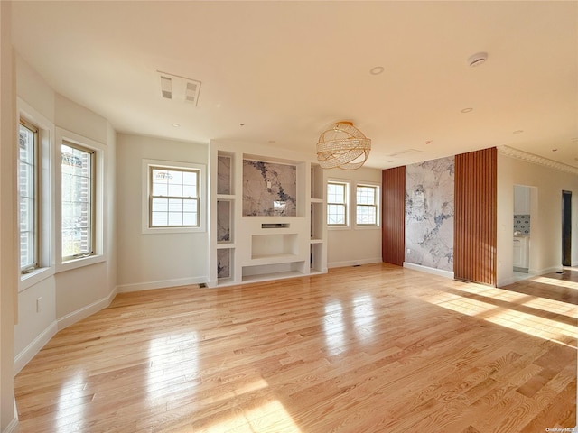 unfurnished living room with plenty of natural light, light hardwood / wood-style floors, and an inviting chandelier