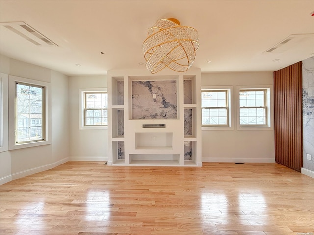 unfurnished living room featuring a notable chandelier and light wood-type flooring