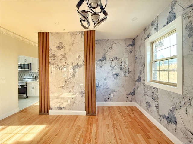 unfurnished room with a chandelier, crown molding, and light hardwood / wood-style floors