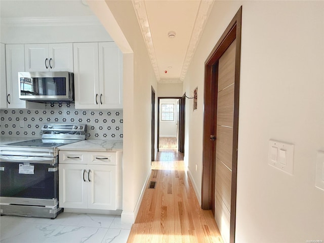 kitchen with decorative backsplash, white cabinetry, stainless steel appliances, and light hardwood / wood-style flooring