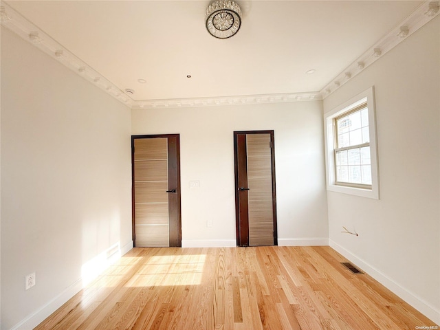 unfurnished bedroom with hardwood / wood-style floors and crown molding