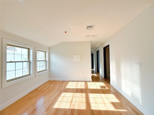 spare room with light hardwood / wood-style floors and vaulted ceiling