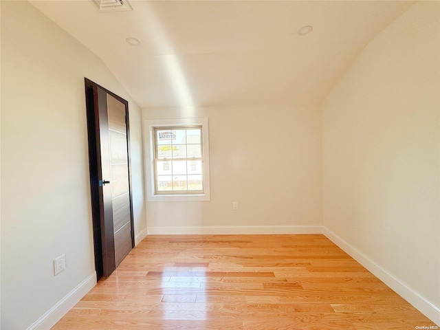 spare room featuring light hardwood / wood-style floors and vaulted ceiling