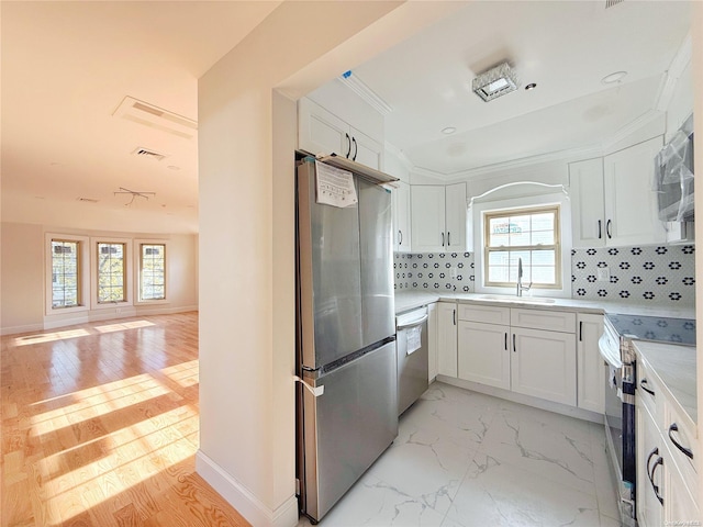 kitchen featuring white cabinets, a wealth of natural light, backsplash, and appliances with stainless steel finishes