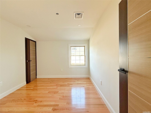 empty room featuring vaulted ceiling and light wood-type flooring