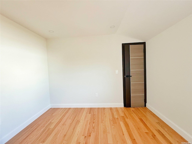 spare room with lofted ceiling and hardwood / wood-style flooring