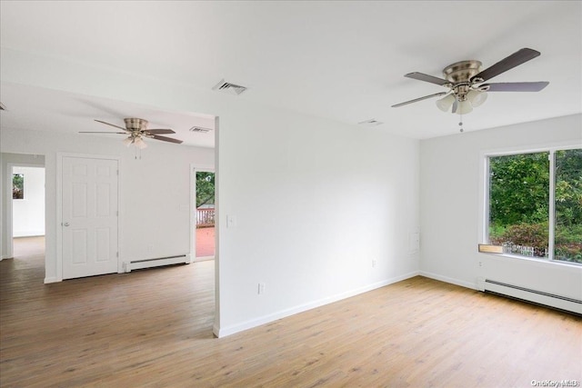 empty room featuring light hardwood / wood-style floors, a healthy amount of sunlight, and a baseboard heating unit