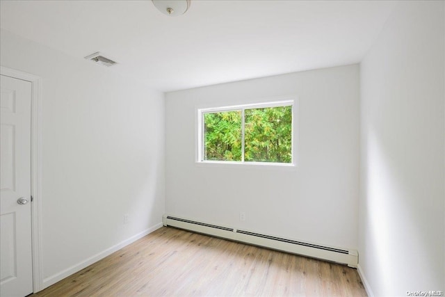 empty room with light wood-type flooring and a baseboard heating unit