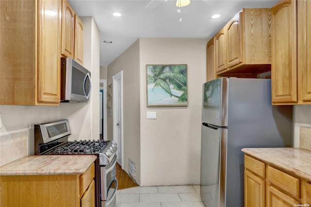 kitchen with light tile patterned floors, light brown cabinets, stainless steel appliances, and ceiling fan