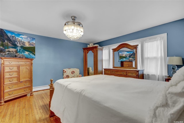 bedroom featuring light hardwood / wood-style floors, baseboard heating, and a notable chandelier