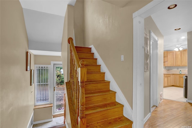 stairs featuring hardwood / wood-style flooring and ceiling fan