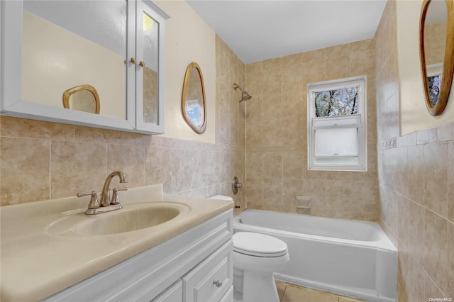 full bathroom featuring vanity, tile patterned floors, tiled shower / bath combo, toilet, and tile walls