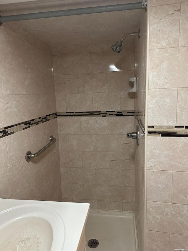 bathroom with tiled shower and sink