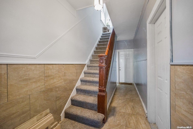 stairway featuring tile walls