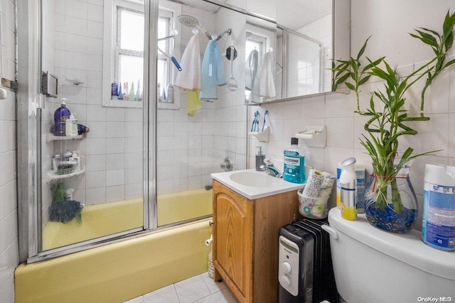 full bathroom featuring vanity, toilet, bath / shower combo with glass door, and tile walls