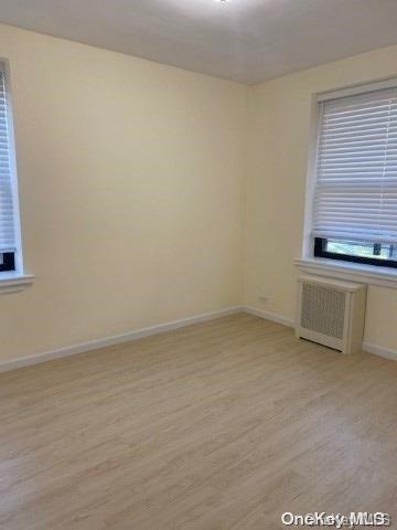 unfurnished room featuring radiator heating unit and light hardwood / wood-style flooring