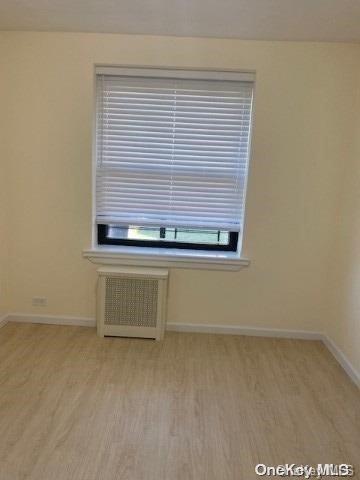 unfurnished room featuring light hardwood / wood-style flooring and radiator heating unit