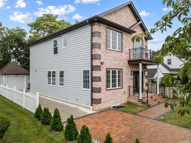 back of property with a patio, a balcony, a garage, and an outdoor structure