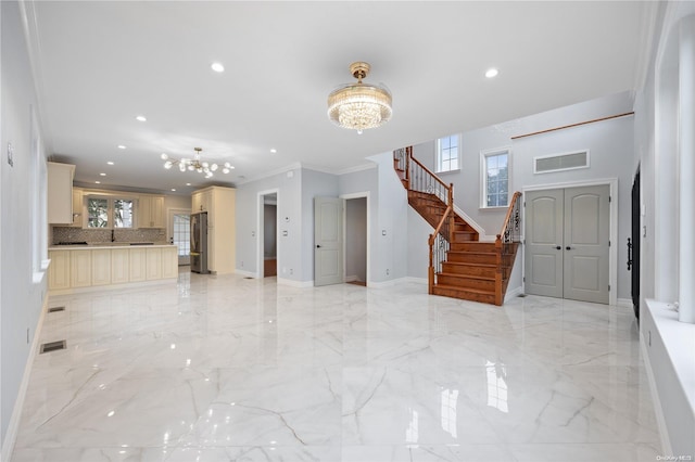 unfurnished living room featuring ornamental molding and a notable chandelier