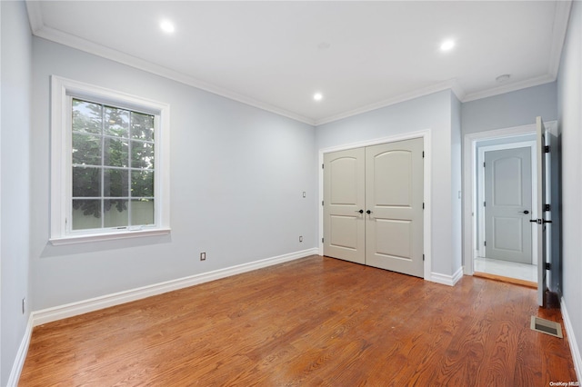 unfurnished bedroom featuring light wood-type flooring, a closet, and crown molding