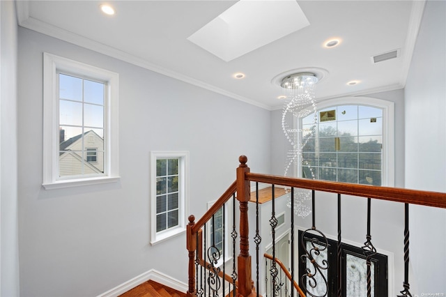 staircase with plenty of natural light, ornamental molding, and a skylight