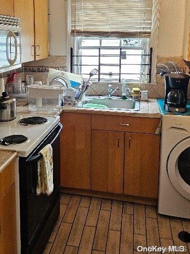 kitchen featuring white electric range, sink, and washer / clothes dryer