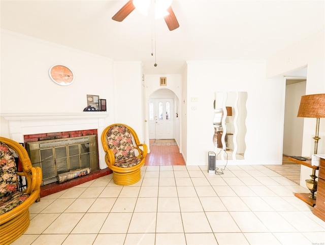 interior space featuring ceiling fan, crown molding, a fireplace, and light hardwood / wood-style flooring