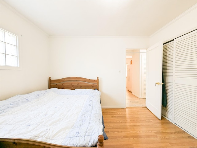 bedroom featuring light hardwood / wood-style floors, a closet, and crown molding