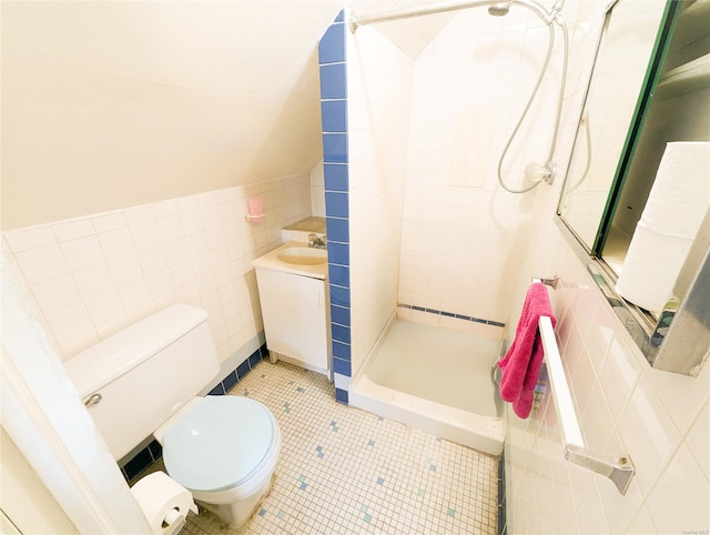 bathroom with tile patterned floors, toilet, tiled shower, vanity, and tile walls