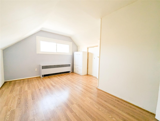 bonus room featuring light hardwood / wood-style floors, radiator heating unit, and vaulted ceiling