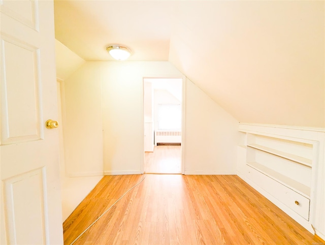 bonus room with radiator heating unit, wood-type flooring, and vaulted ceiling