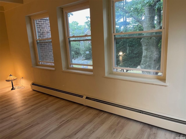 unfurnished room featuring baseboard heating and light hardwood / wood-style flooring