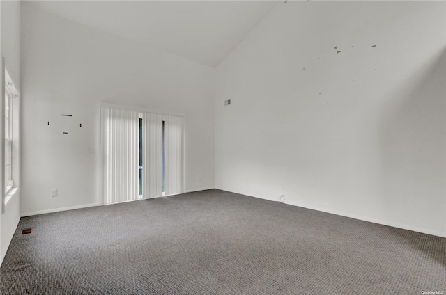 empty room with carpet floors and high vaulted ceiling