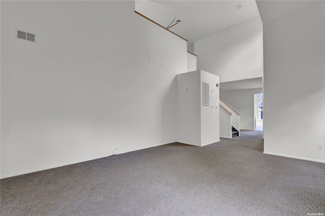 carpeted spare room featuring a high ceiling