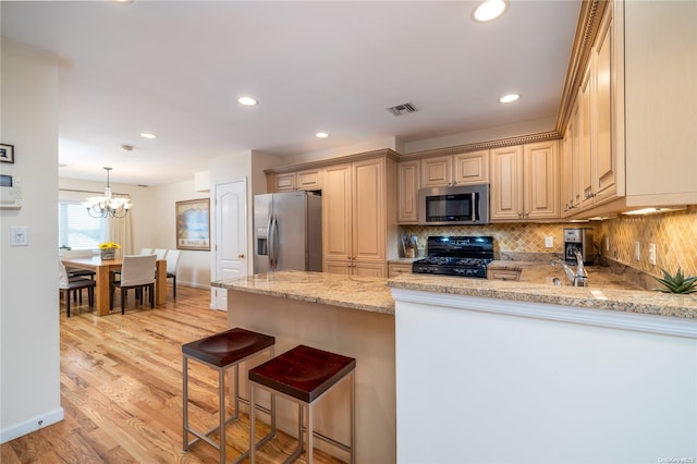 kitchen featuring light stone countertops, a kitchen breakfast bar, kitchen peninsula, stainless steel appliances, and light hardwood / wood-style flooring