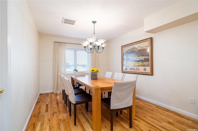 dining area with an inviting chandelier and light hardwood / wood-style flooring