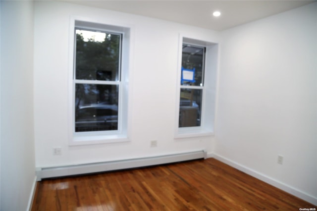 empty room featuring a baseboard radiator and dark wood-type flooring