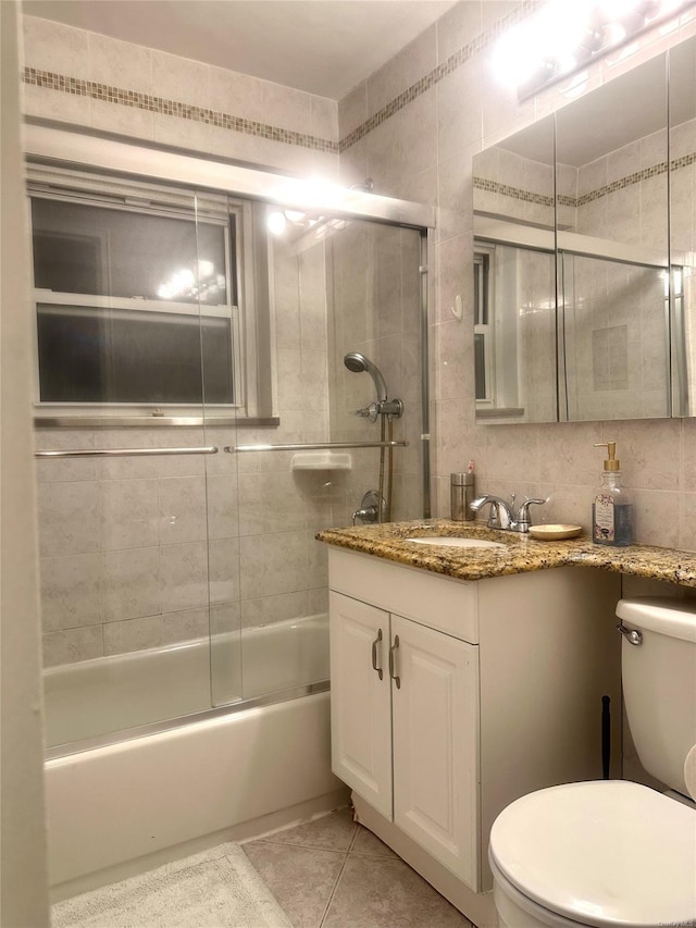 full bathroom featuring tile patterned floors, combined bath / shower with glass door, vanity, and toilet