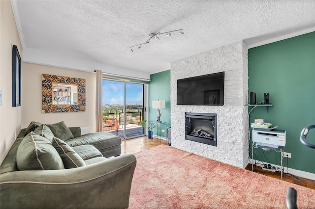 living room featuring a fireplace, rail lighting, and a textured ceiling