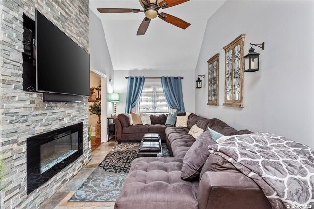 living room featuring a stone fireplace, ceiling fan, and vaulted ceiling