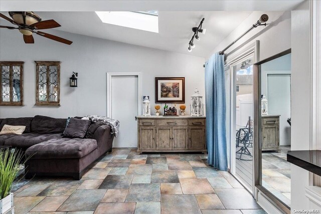 living room with vaulted ceiling with skylight, ceiling fan, and rail lighting