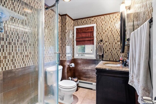 bathroom featuring vanity, tile patterned floors, toilet, baseboard heating, and tile walls