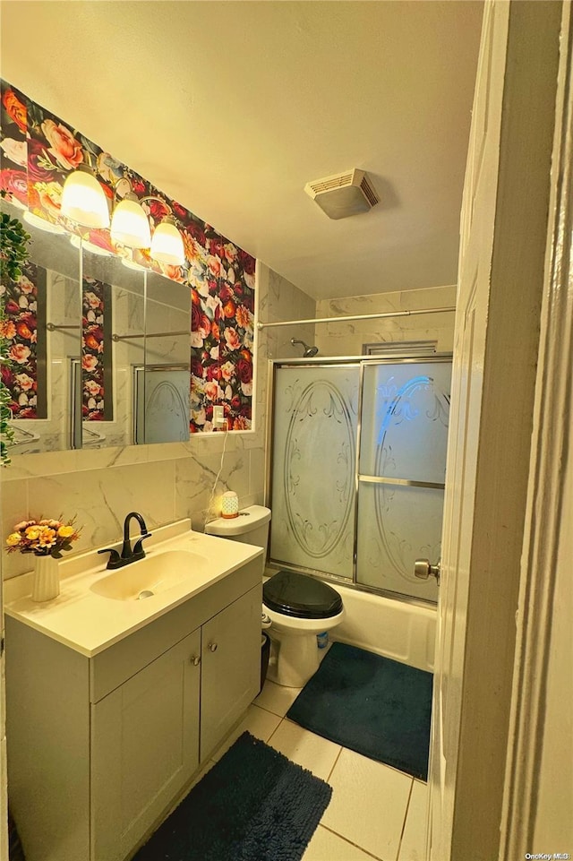 full bathroom featuring combined bath / shower with glass door, backsplash, vanity, tile patterned flooring, and toilet