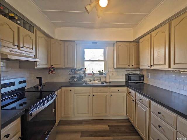 kitchen featuring under cabinet range hood, electric range, dark countertops, and a sink