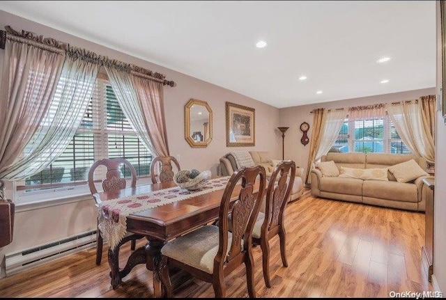 dining area featuring a baseboard heating unit and light wood-type flooring