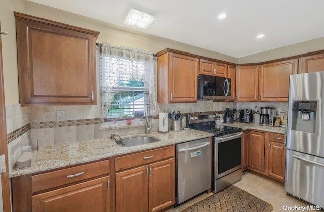 kitchen featuring light stone countertops, sink, stainless steel appliances, decorative backsplash, and light tile patterned floors