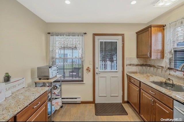 kitchen featuring light stone counters, baseboard heating, a wealth of natural light, and sink